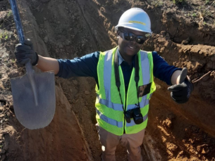 Potego in a pit holding a shovel